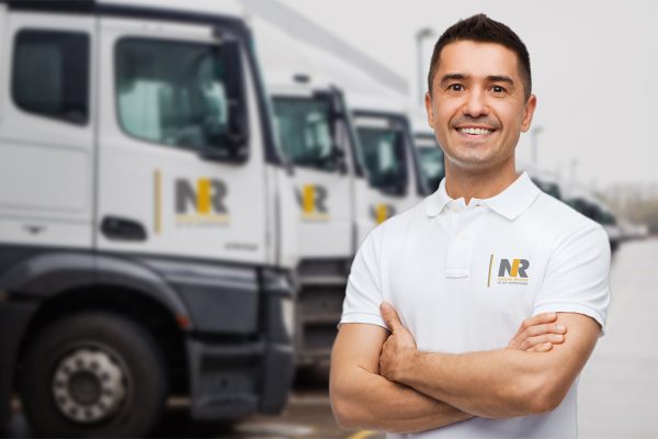 NRI Polo Shirt on man with crossed arms in front of trucks